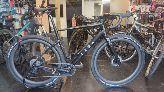 Black Fara drop-bar gravel bike with wide knobbly Schwalbe tyres, disc brakes and a wide-range cassette at the Bike Clinique workshop